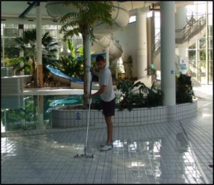 Un jeune homme appliquant le produit "Surefoot" de Belzona sur le carrelage d'une piscine.